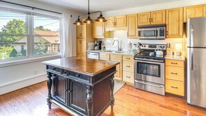 Una cocina con armarios de madera, un refrigerador de acero inoxidable, un microondas y una estufa.