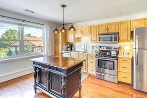 A kitchen with wooden cabinets, stainless steel appliances, and a large window.