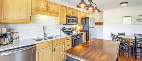 A kitchen with wooden cabinets, stainless steel appliances, and a large wooden island.