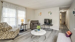 Un salon comprenant un canapé, un fauteuil, un téléviseur, une table basse et des objets de décoration.