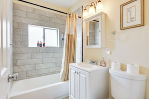 A bathroom with a bathtub, a sink, a toilet, and a window. - Las Cruces Home w/ Fenced Yard: Recently Remodeled (Las Cruces)