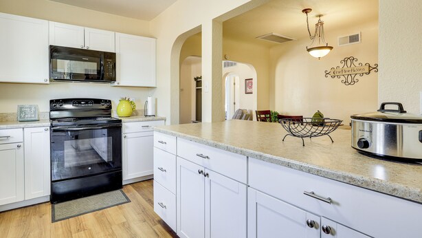 A modern kitchen with white cabinets, a black stove, a microwave, and a granite countertop. - Las Cruces Home w/ Fenced Yard: Recently Remodeled (Las Cruces)