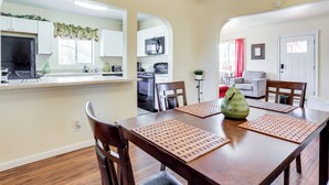 A dining area with a wooden table, chairs, and placemats. There is a kitchen visible through an archway in the background. - Las Cruces Home w/ Fenced Yard: Recently Remodeled (Las Cruces)