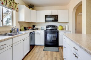 A kitchen with white cabinets, a black oven, a microwave, and a coffee maker. - Las Cruces Home w/ Fenced Yard: Recently Remodeled (Las Cruces)