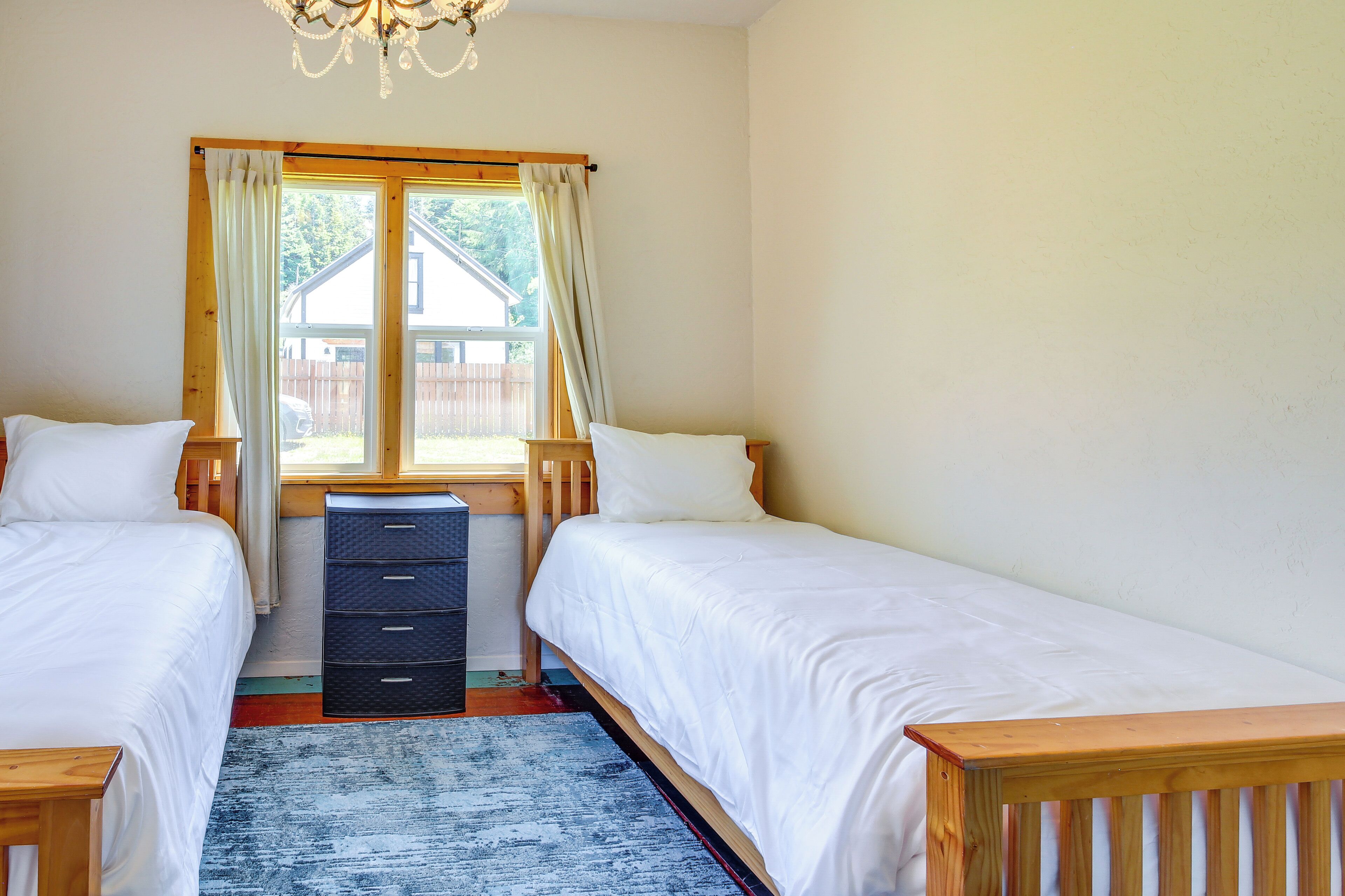 A bedroom with two single beds, a wooden desk, and a window with curtains.