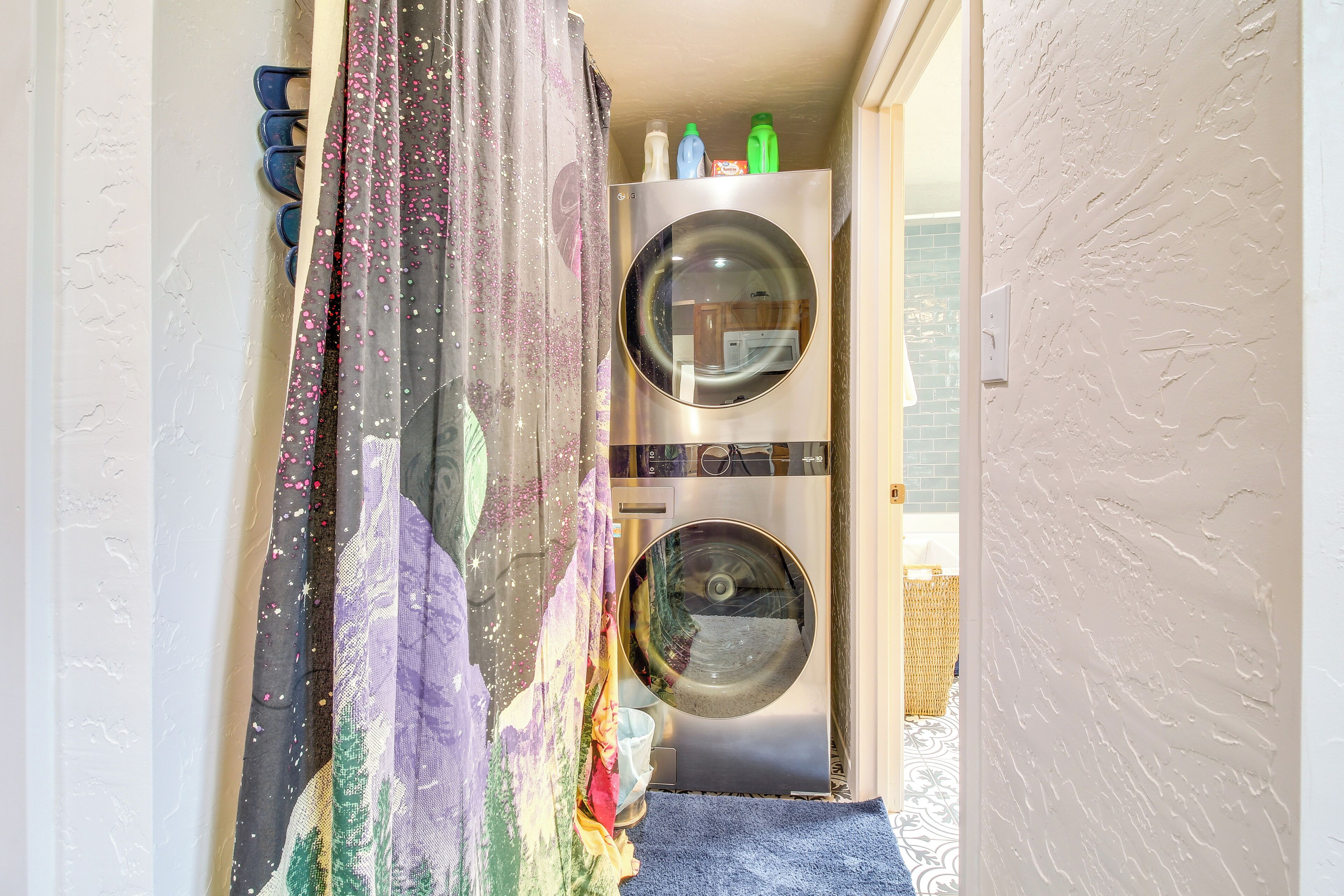 A laundry area with two washing machines, a drying rack, and a colorful curtain.