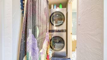 A laundry area with two washing machines, a drying rack, and a colorful curtain.