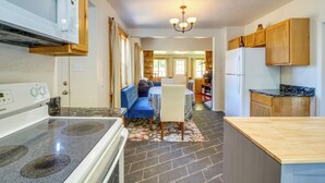 Una cocina con estufa, microondas, armarios de madera y zona de comedor con sofá azul y mesa.