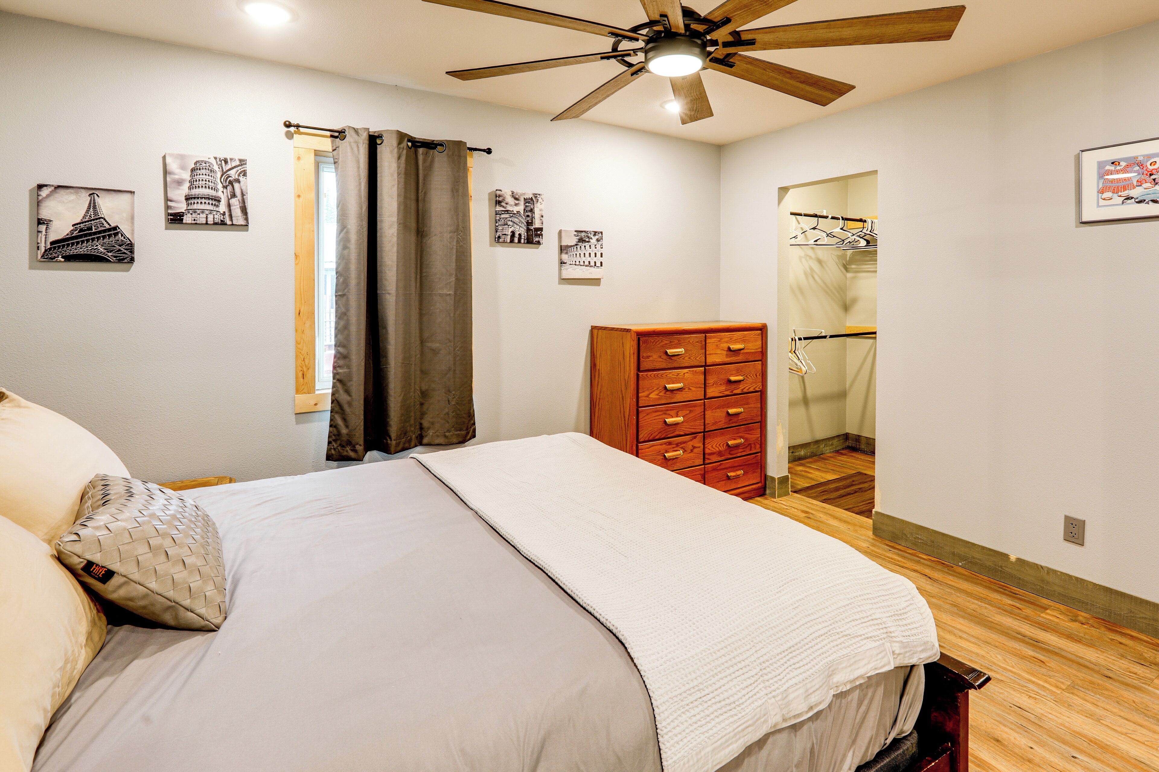 Une chambre à coucher avec un lit, une commode en bois et un ventilateur de plafond.