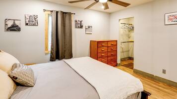 Une chambre à coucher avec un lit, une commode en bois et un ventilateur de plafond.