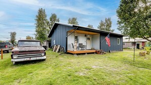 A single-story building with a porch and an American flag. - Walk to Dtwn: Dog-friendly Retreat in Fairbanks! (Fairbanks)