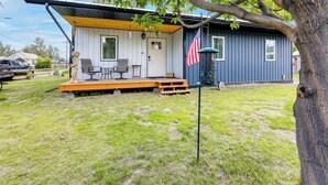 A small, single-story building with a porch, a flag, and a tree. - Walk to Dtwn: Dog-friendly Retreat in Fairbanks! (Fairbanks)