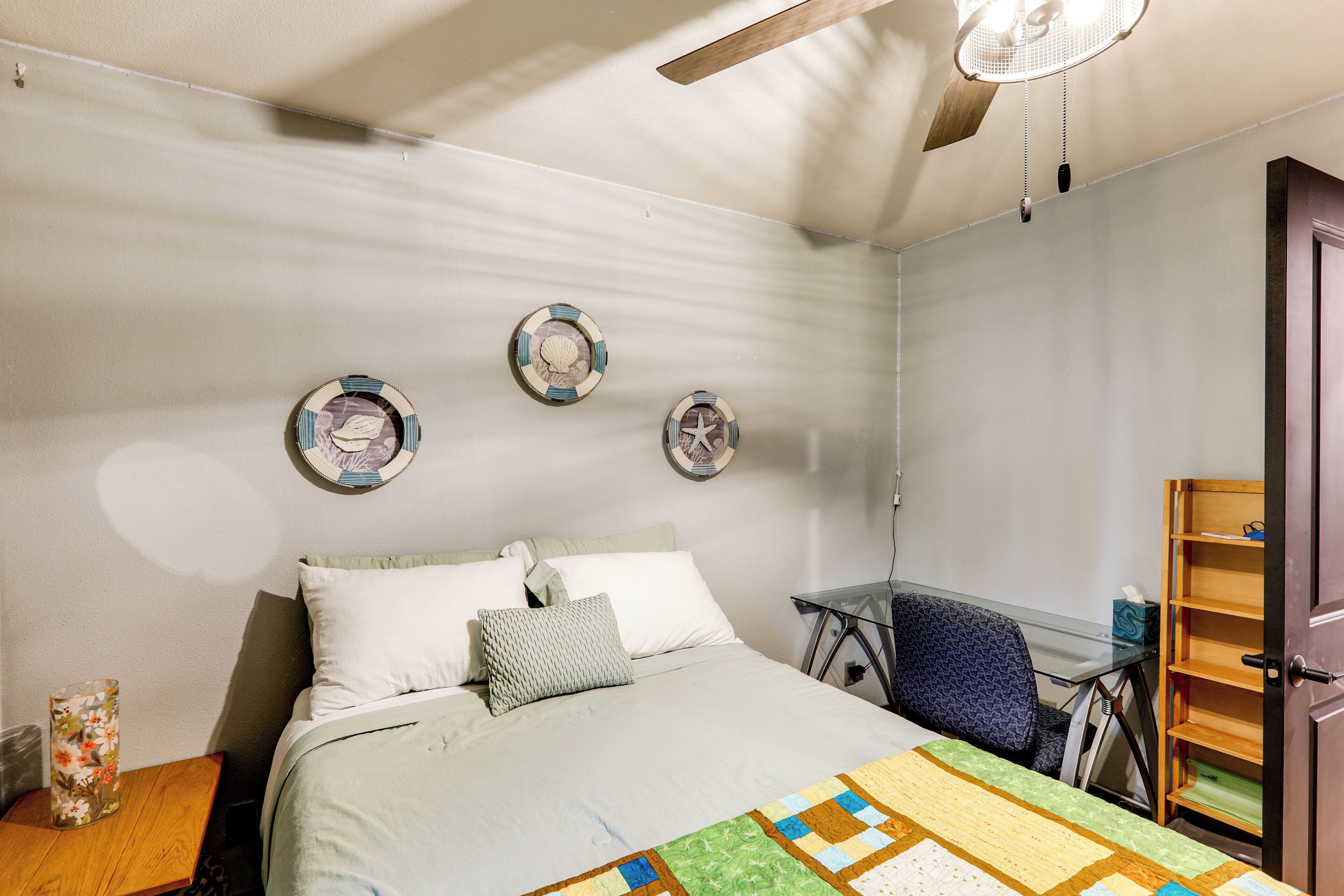 A bedroom with a bed, a desk, and a chair. There are decorative plates on the wall.