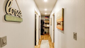 A hallway with a 'Love Grows Here' sign, a patterned rug, and a painting on the wall. - Walk to Dtwn: Dog-friendly Retreat in Fairbanks! (Fairbanks)