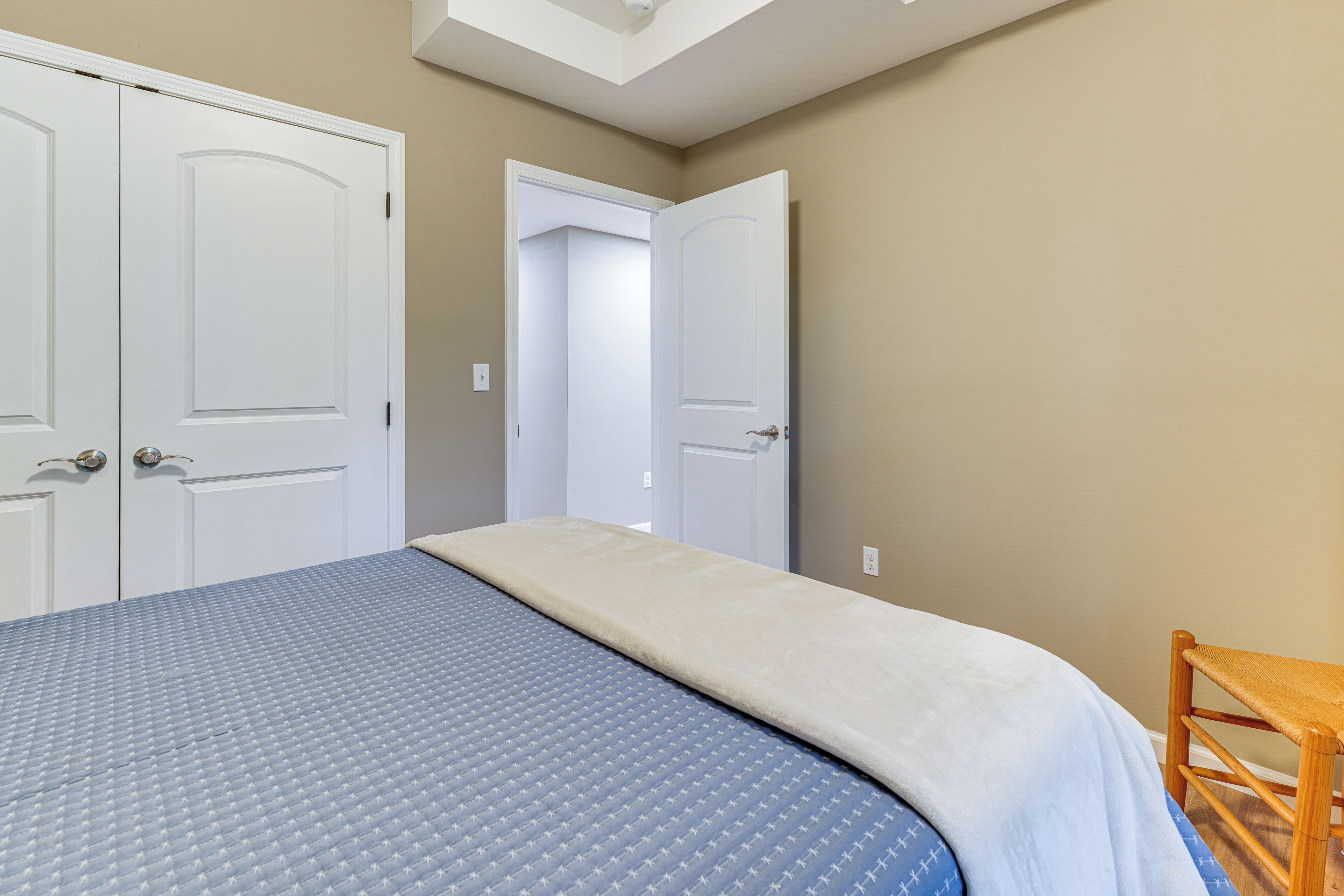A bedroom with a bed, two doors, and a chair.