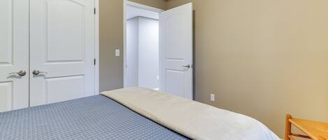 A bedroom with a bed, two doors, and a chair.