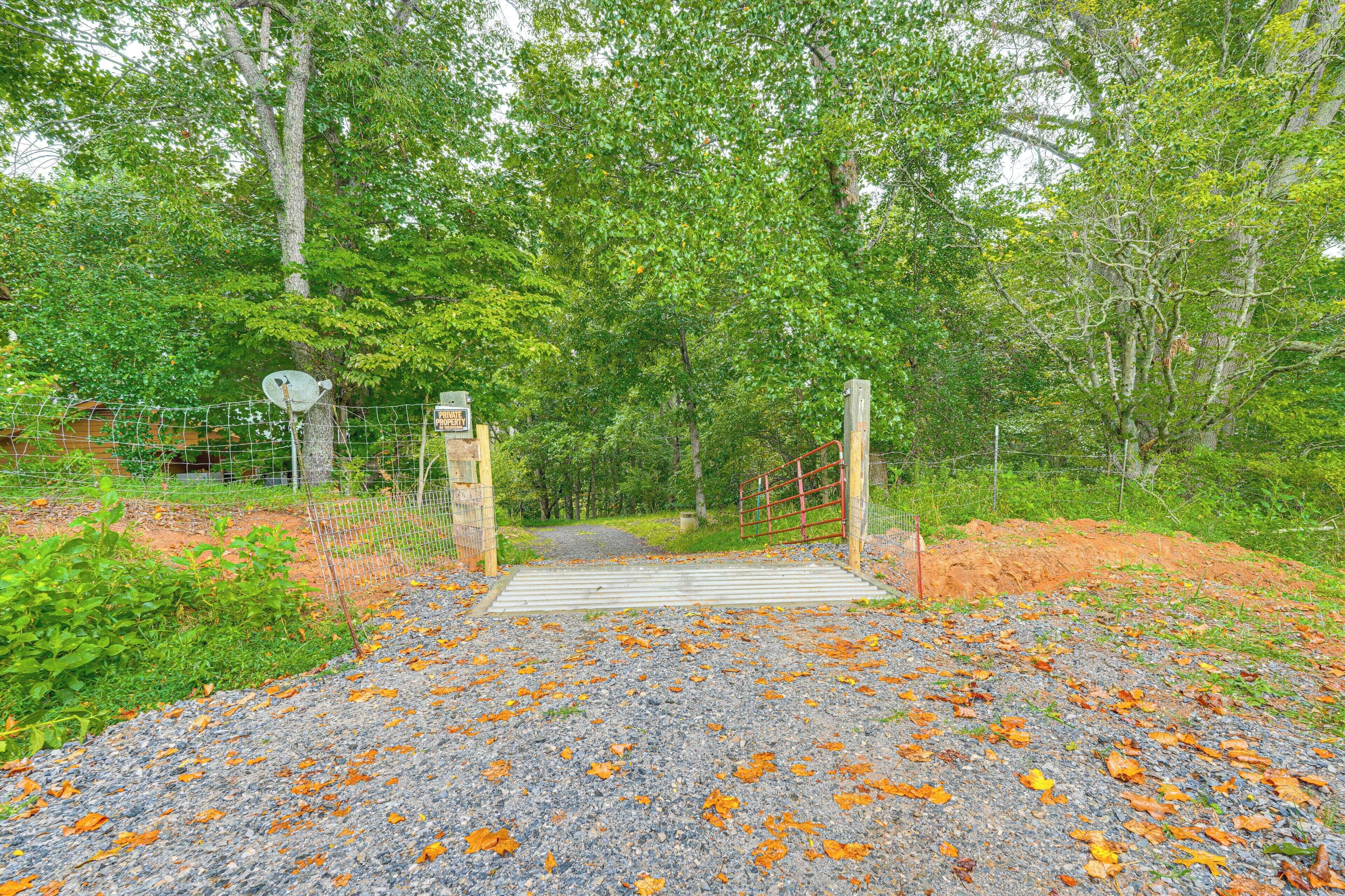 A gravel path leading to a gated entrance surrounded by trees and greenery.