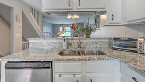 A kitchen with white cabinets, a granite countertop, a stainless steel sink, a dishwasher, and a toaster. - Norcross Townhome ~ 18 Mi to Dtwn Atlanta! (Norcross)