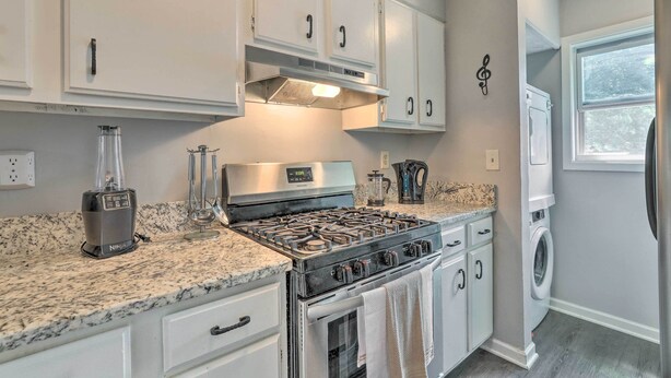 A kitchen with white cabinets, a gas stove, a blender, and a washing machine. - Norcross Townhome ~ 18 Mi to Dtwn Atlanta! (Norcross)