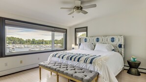 Un dormitorio con un ventanal grande, una cama con cabecera estampada y un banco.