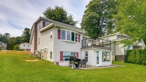 Una casa de dos pisos con balcón, un patio con mobiliario exterior y un césped bien cuidado.