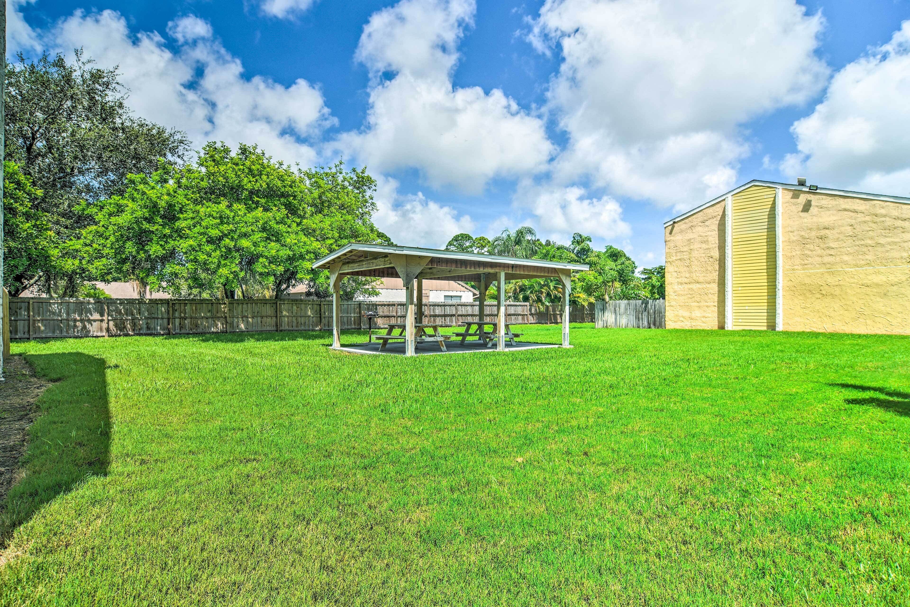 A backyard with a covered picnic area, a shed, and a wooden fence.