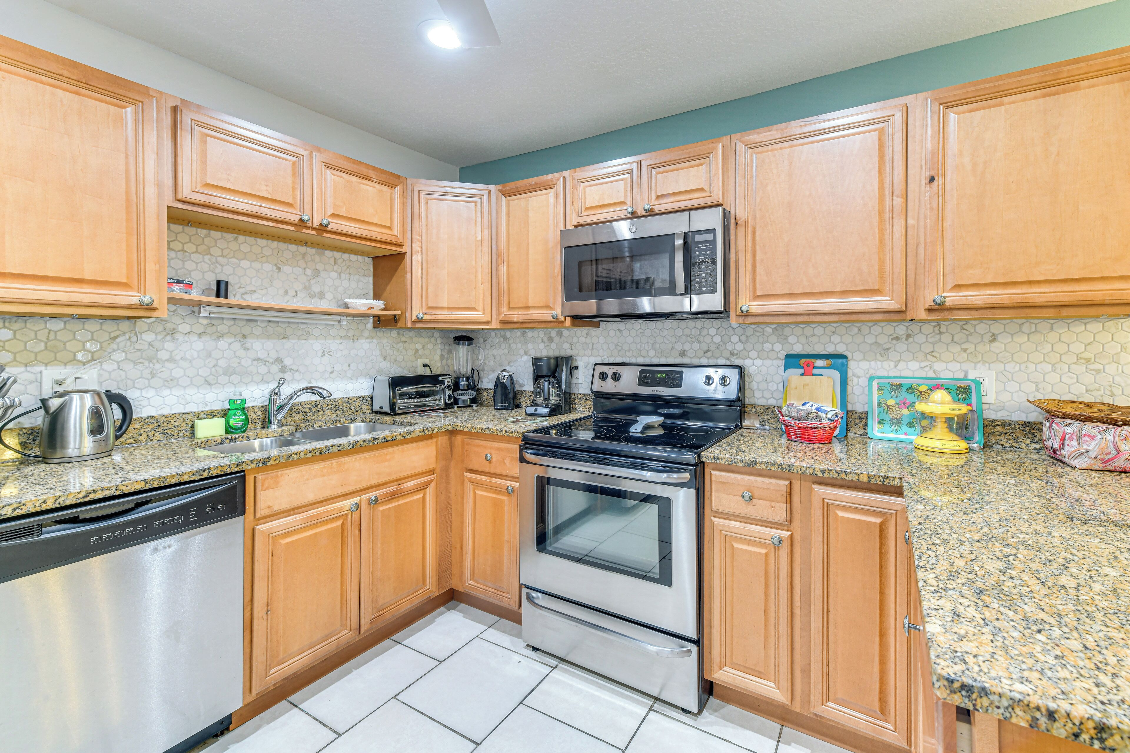 A kitchen with wooden cabinets, a stainless steel dishwasher, a double oven, a microwave, and a granite countertop.
