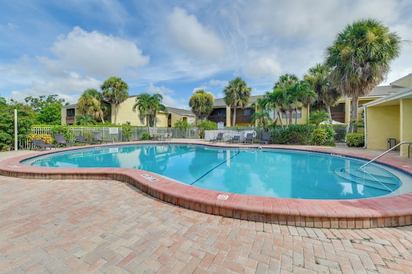 A swimming pool with a brick border, surrounded by palm trees and a fence. - Explore Sarasota: Condo w/ Pool Access, Near Dtwn (Sarasota)