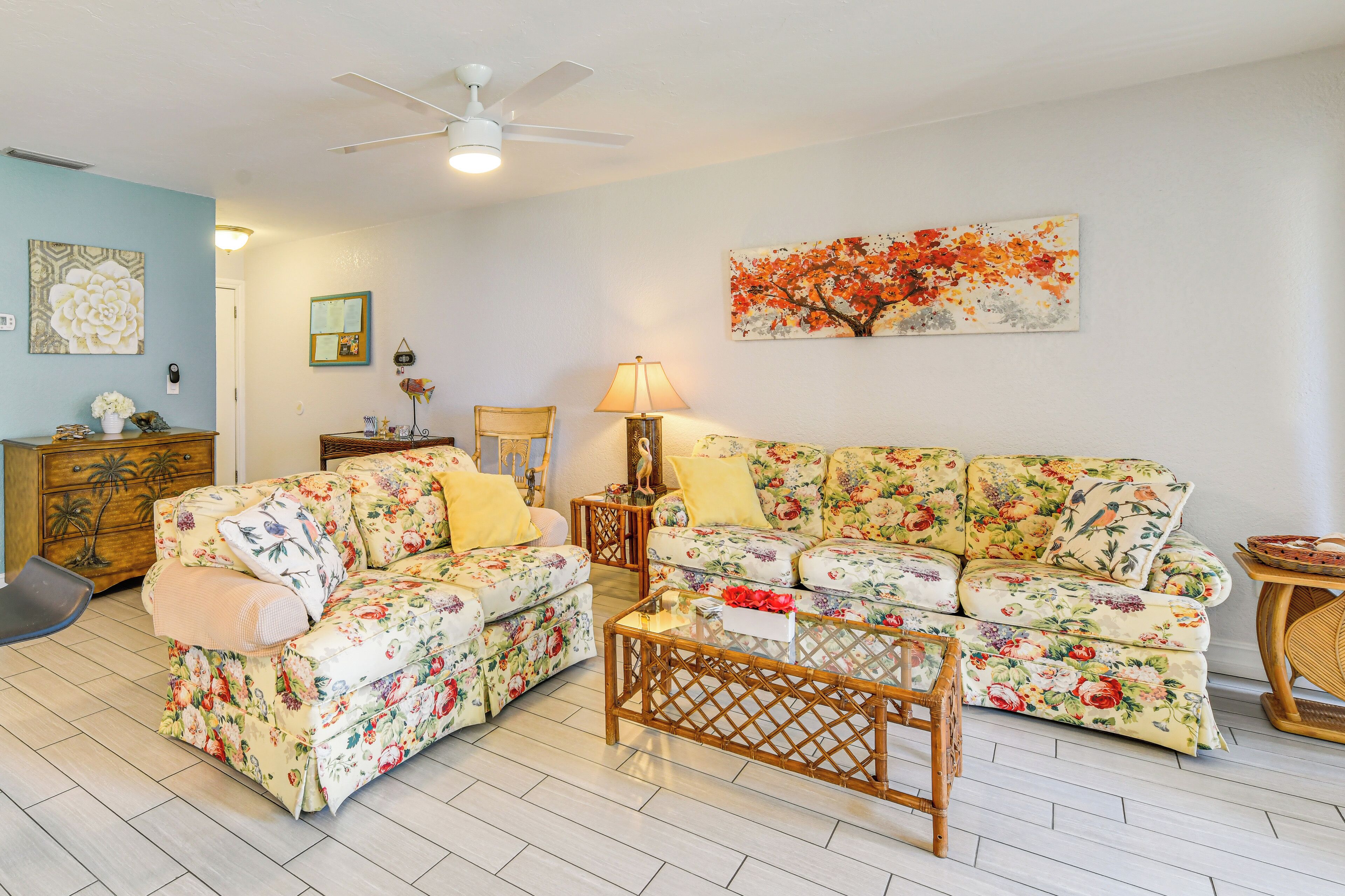 Una sala de estar con sofás de estampado floral, una mesa de centro de madera y un ventilador de techo.