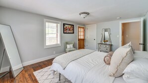 A bedroom with a large bed, a dresser, a chair, and a door. - Pool & Deck: Pond-view Getaway in Newnan! (Newnan)