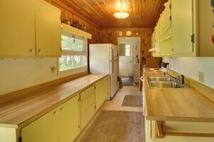 Una cocina compacta con armarios de madera, un refrigerador, un lavamanos y una ventana.
