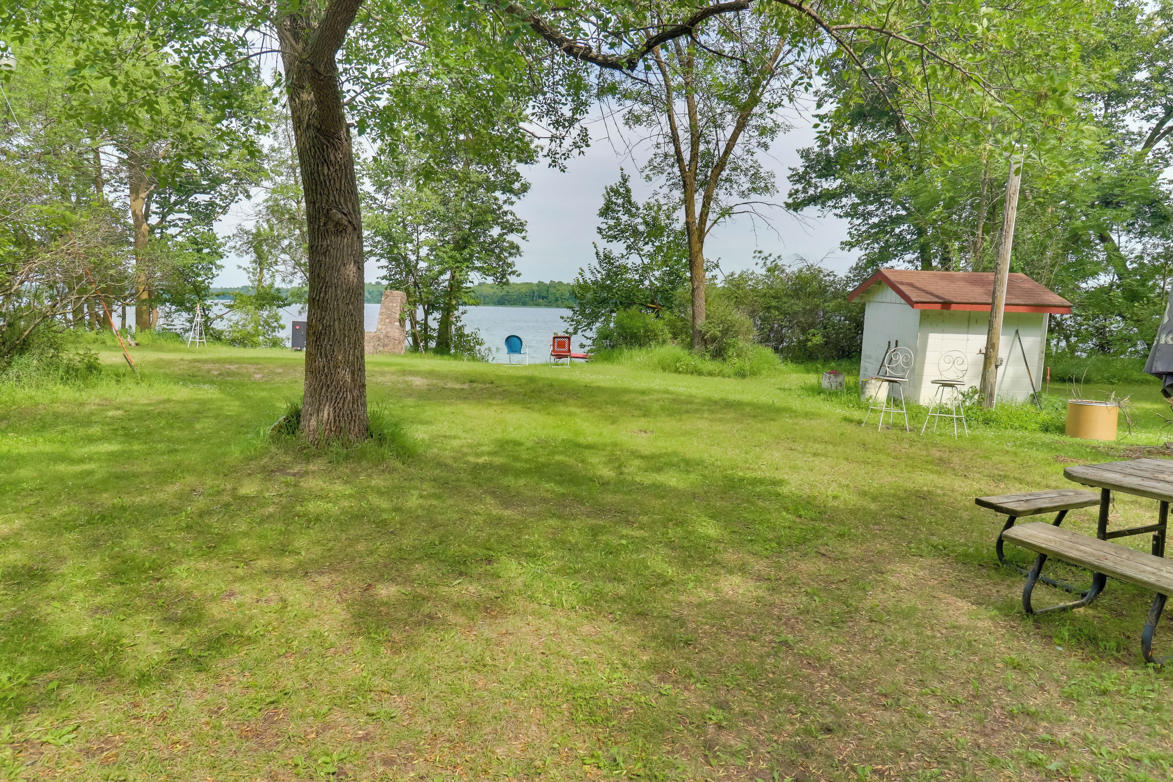 A grassy area with a picnic table, a small shed, and a blue structure in the background.