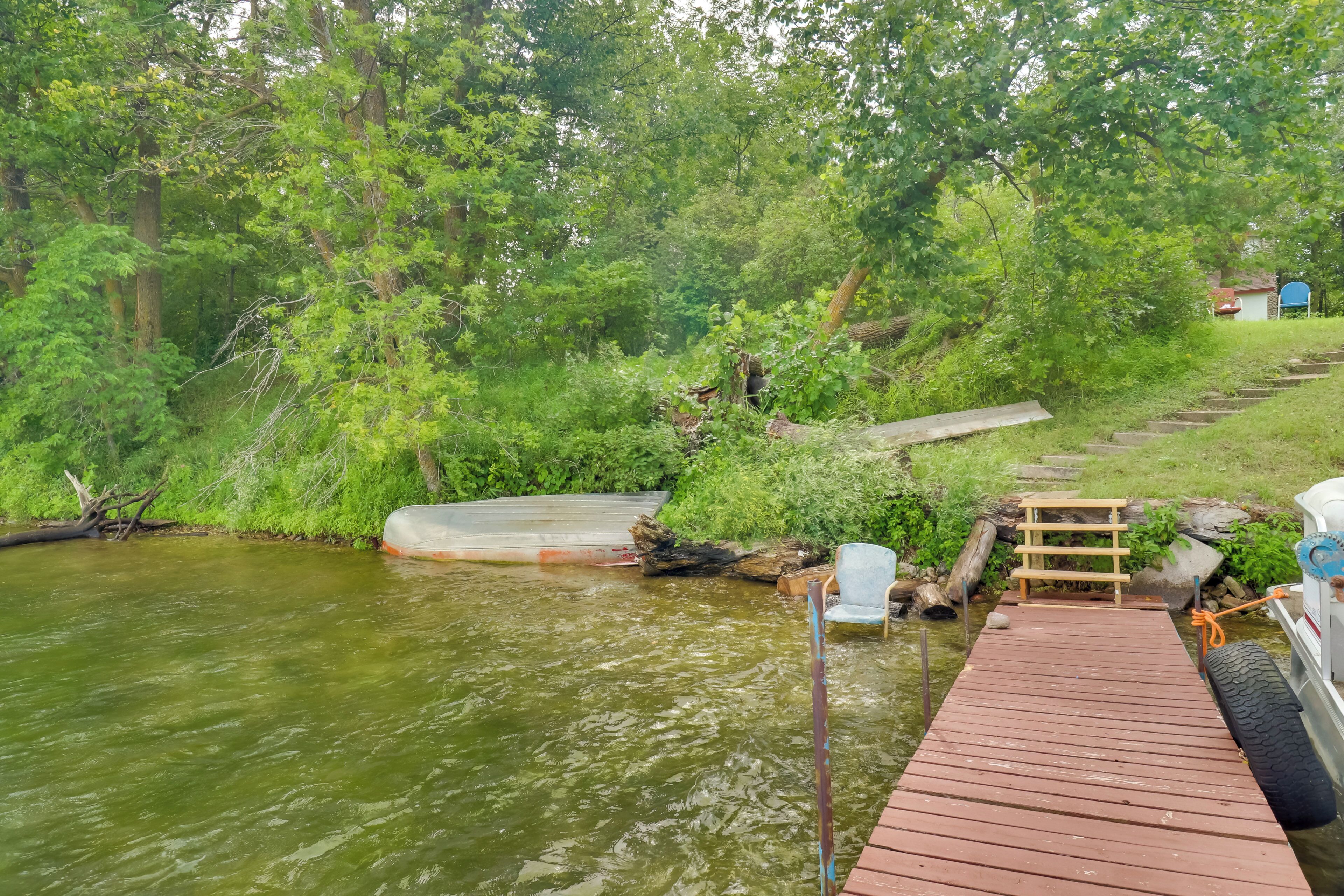 Eine Holzstege reicht in einen Fluss, umgeben von dichtem Grün und Bäumen.