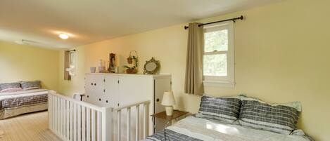 A bedroom with two beds, a dresser, a nightstand, a window with curtains, and a ceiling light.
