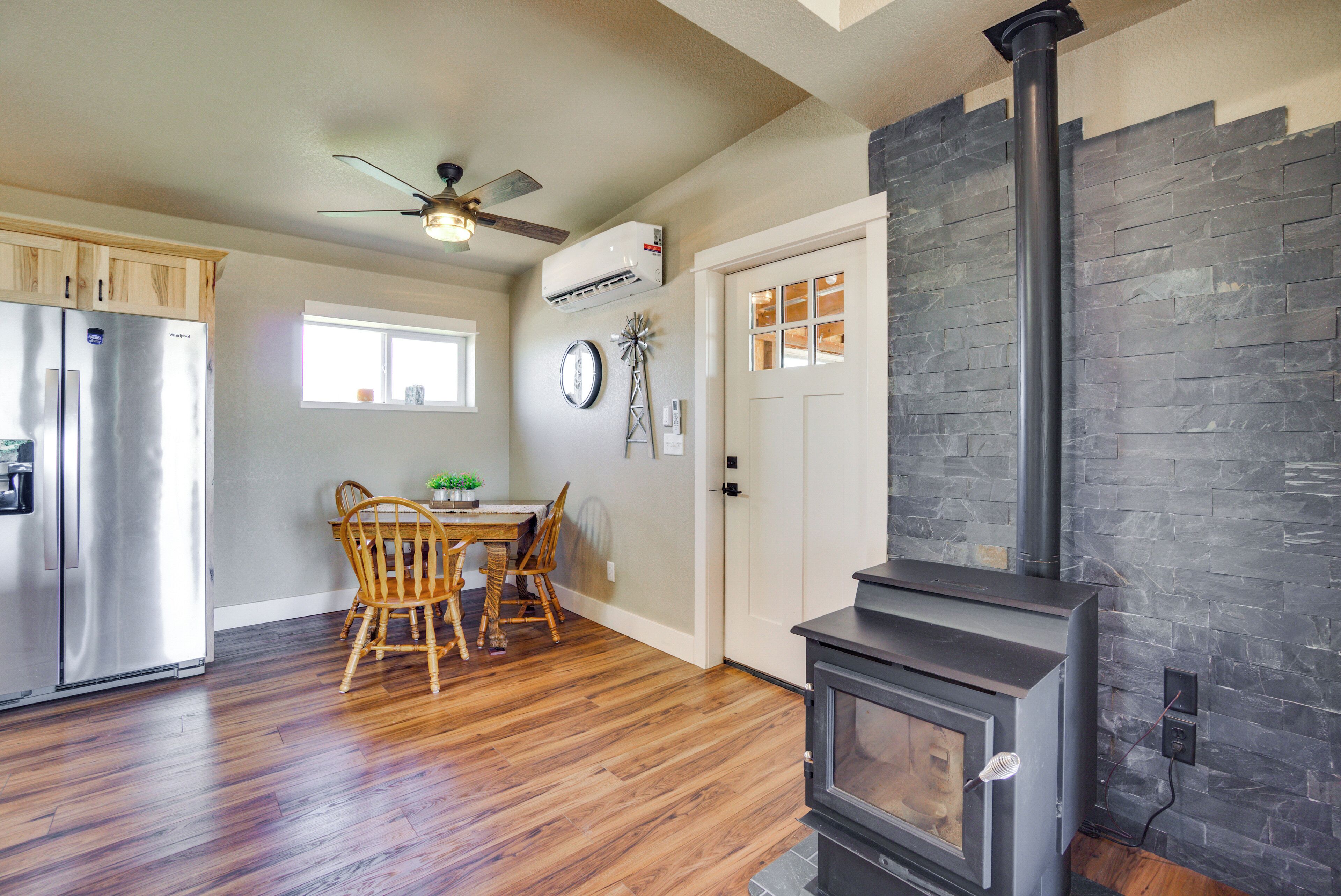 A kitchen with a built-in wood stove, wooden cabinets, a dining table with chairs, and a ceiling fan.