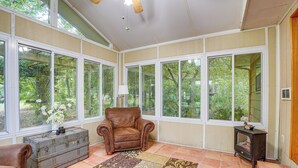 A sunroom with large windows, a leather chair, a vintage trunk, and a small heater. - Quiet Retreat in Bluffton: Fish, Hike & Golf (Bluffton)