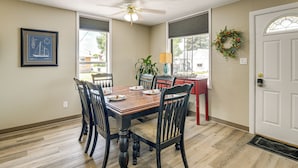 A dining room with a wooden table and chairs, a ceiling fan, a framed nautical chart, and a wreath on the wall.