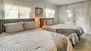 A room with two beds, a radiator, a lamp, and a door leading to an outdoor area.