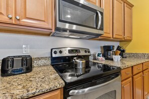 Una cocina equipada con microondas, estufa, tostadora y encimera de granito.