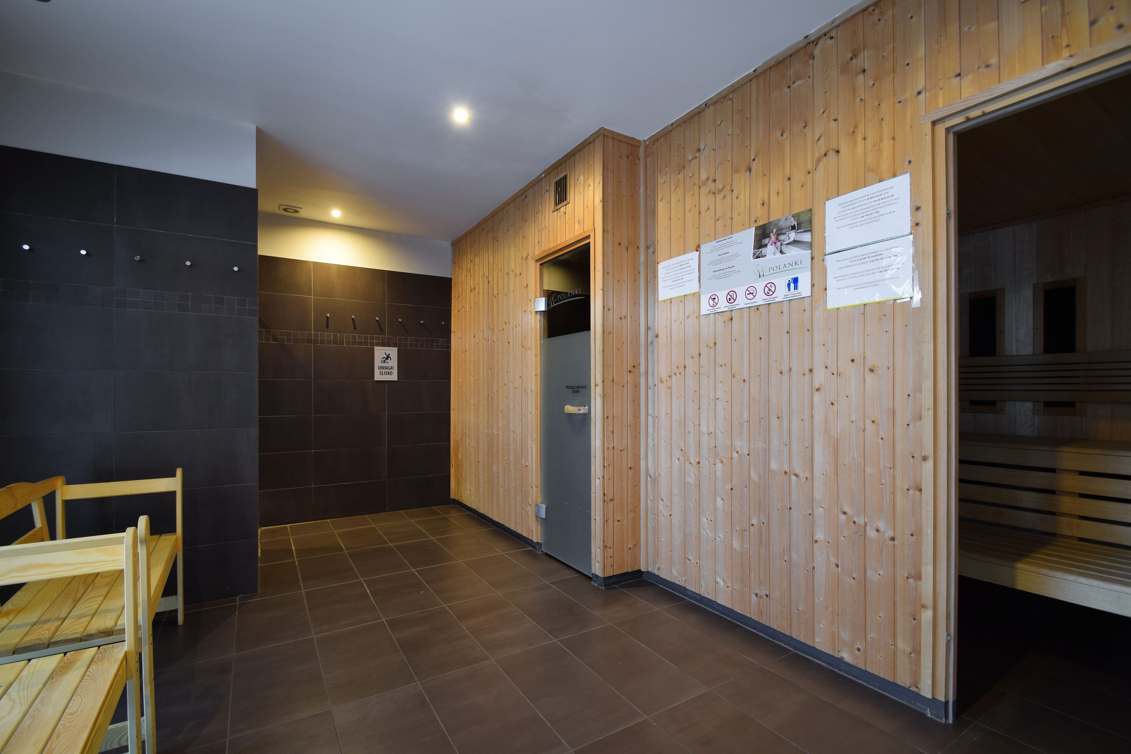 A sauna room with wooden walls, a bench, and a door leading to another room.