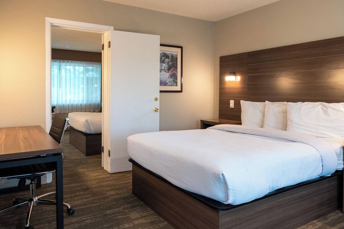 A hotel room with a bed, a desk, and a chair.