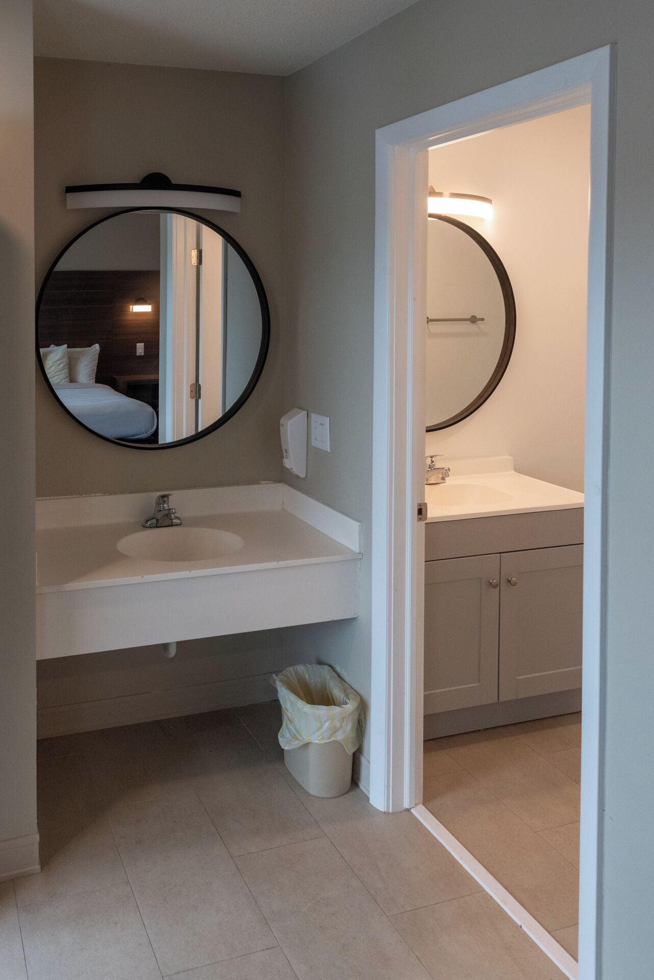 Un baño con un espejo redondo, un lavabo y un inodoro.