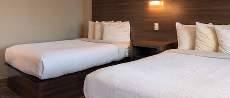 Two twin beds with white linens in a hotel room.