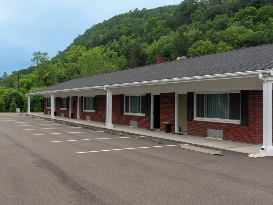 A motel with a covered parking area and a brick building.