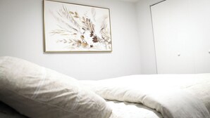 A bedroom with a bed, a white wall, and a framed artwork above the bed. - Luxury 2 bedroom basement (Winnipeg)