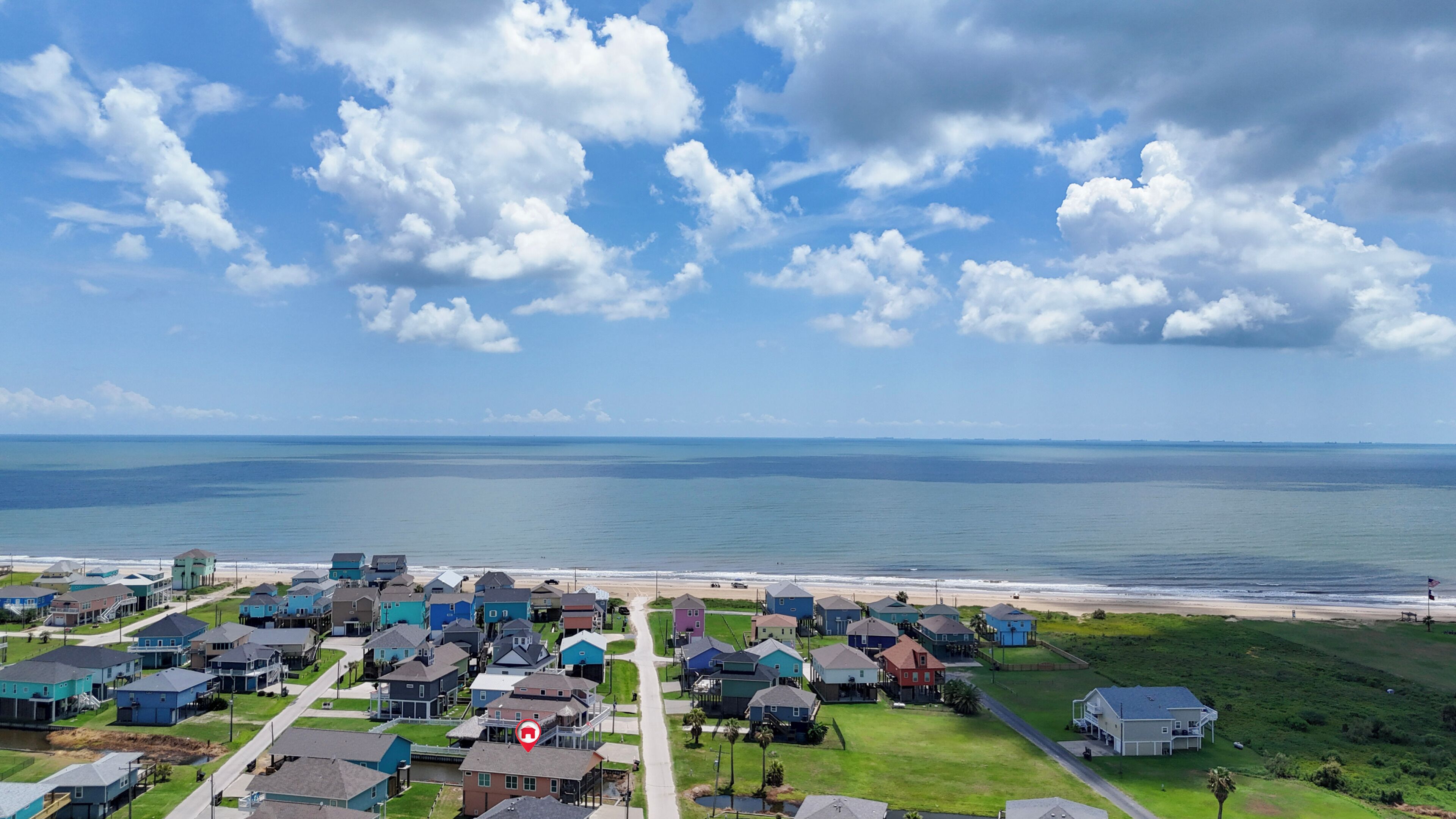 A coastal residential area with houses, a beach, and a clear sky.