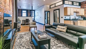 A modern living room with a black leather sofa, a coffee table, and a patterned rug. - 2BR-1BA, Sleeps 4 | Downtown Ames (Ames)