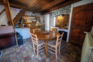 Una cocina rústica con una mesa de madera, sillas y una chimenea de piedra.