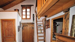 A narrow hallway with wooden doors and a ladder leading to a loft area. - Mountain house near Méribel (Brides-les-Bains)