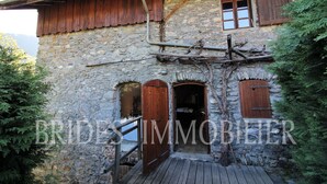 A stone building with wooden shutters, a wooden staircase, and a metal railing. - Mountain house near Méribel (Brides-les-Bains)